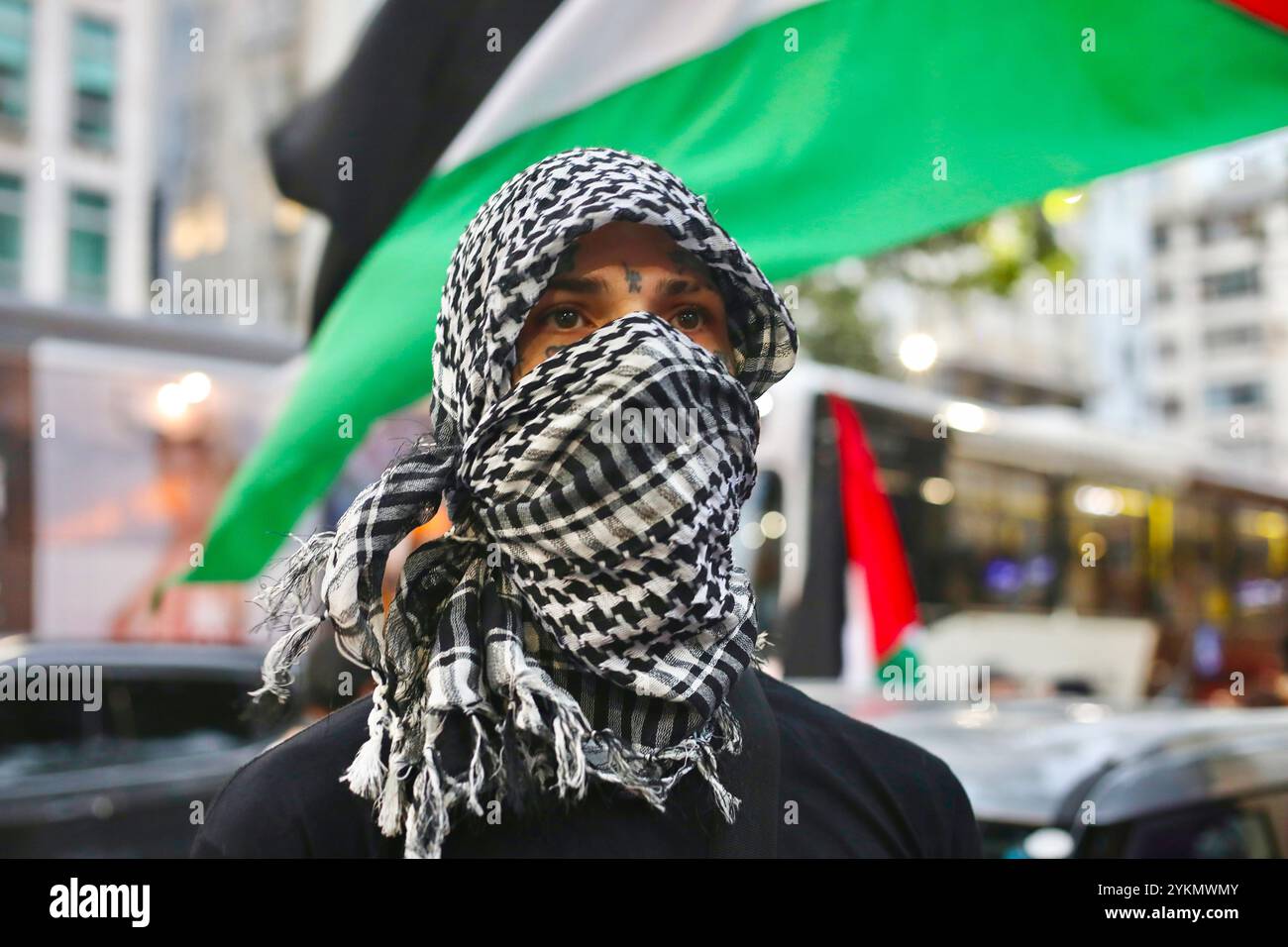 Ein Demonstrant mit palästinensischem Schal versammelt sich vor dem US-Konsulat in Rio de Janeiro, um einen Waffenstillstand in Gaza zu fordern und die Palästinenser zu unterstützen. In Rio de Janeiro sehen die Einwohner der Favela Ähnlichkeiten zwischen der Behandlung ihrer Gemeinde und der Behandlung der Palästinenser im Westjordanland. Einige Favelas haben sogar eine Straße mit dem Spitznamen "Gazastreifen" wegen der ständigen Schüsse. In Rio de Janeiro fanden mehrere pro-palästinensische Demonstrationen statt, bei denen Aktivisten aus den Favelas versammelt wurden. Stockfoto