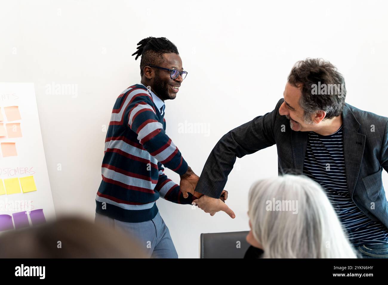 Vielfältige Geschäftsteams teilen während kreativer Besprechungen freudige Momente, multikulturelle Kollegen feiern Erfolge mit authentischen Interaktionen, die m Stockfoto