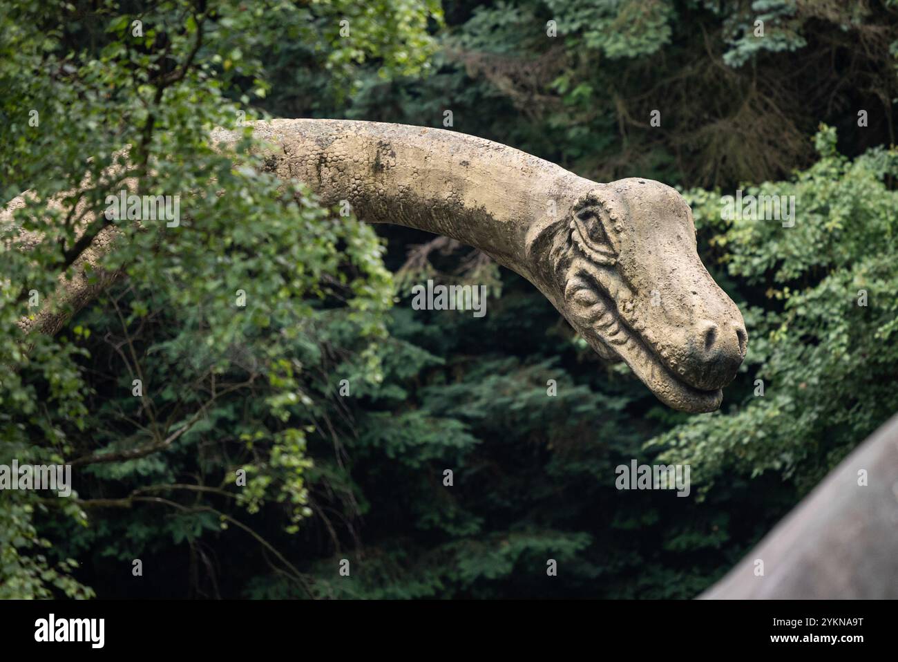 Eine Nahaufnahme einer Dinosaurier-Skulptur in einem Park, die ihr detailliertes Design, ihre lebensechten Farben und ihr lebensechtes Aussehen zeigt und Kreativität mit Paleon verbindet Stockfoto