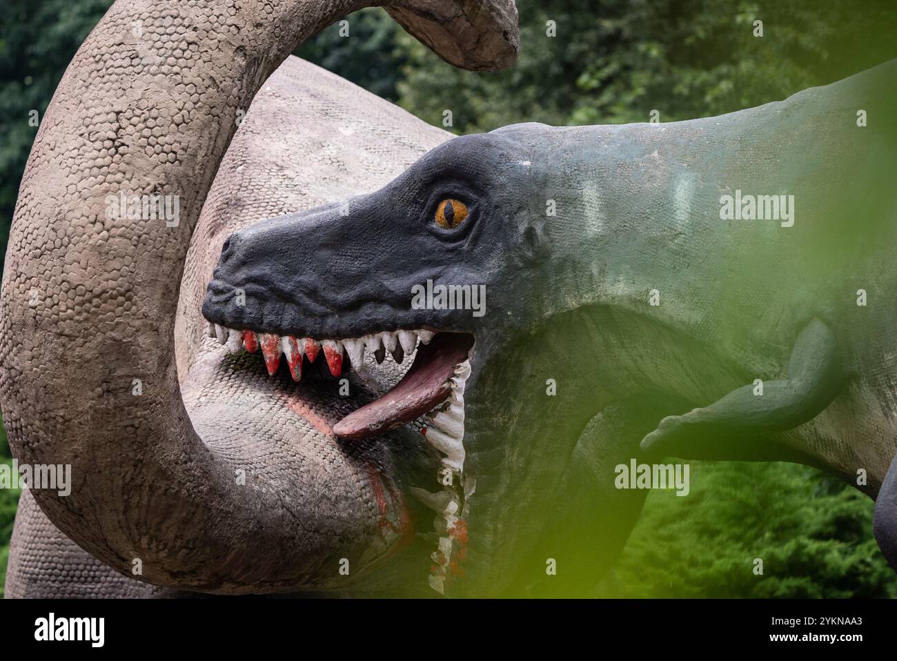 Eine Nahaufnahme einer Dinosaurier-Skulptur in einem Park, die ihr detailliertes Design, ihre lebensechten Farben und ihr lebensechtes Aussehen zeigt und Kreativität mit Paleon verbindet Stockfoto