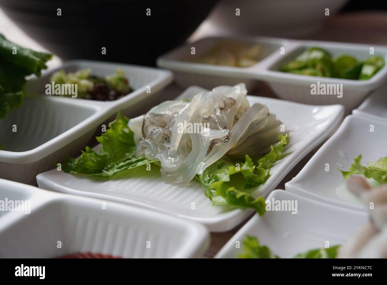 Tintenfisch in Scheiben auf Salatblatt auf weißem Teller auf Holztisch Stockfoto