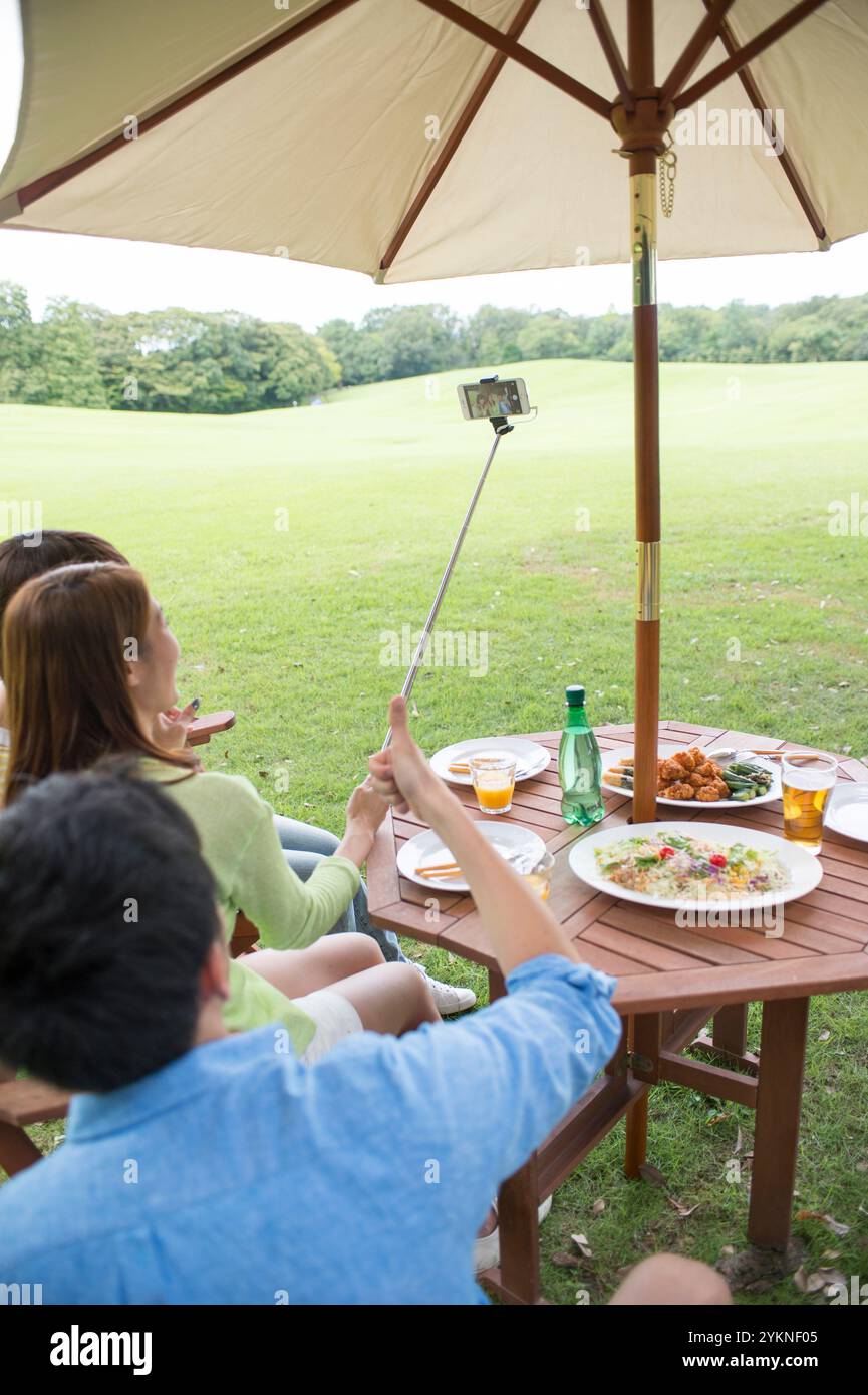 Drei junge Leute fotografieren ihre Mahlzeit bei einem Picknick Stockfoto