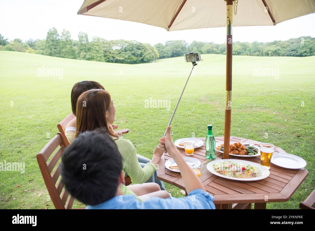 Drei junge Leute fotografieren ihre Mahlzeit bei einem Picknick Stockfoto