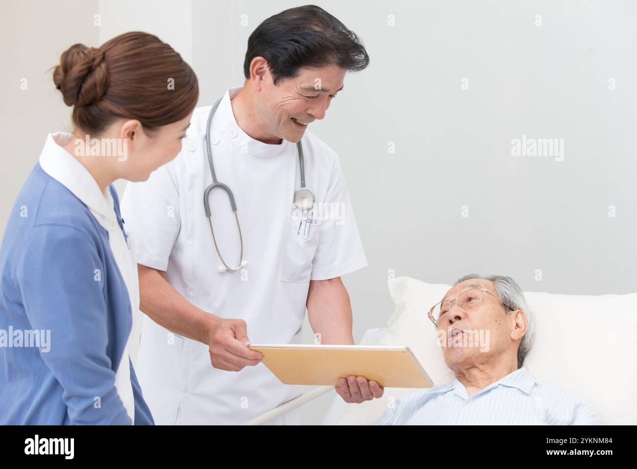 Ärzte, Krankenschwestern und ältere männliche Patienten, die häusliche Pflege leisten Stockfoto