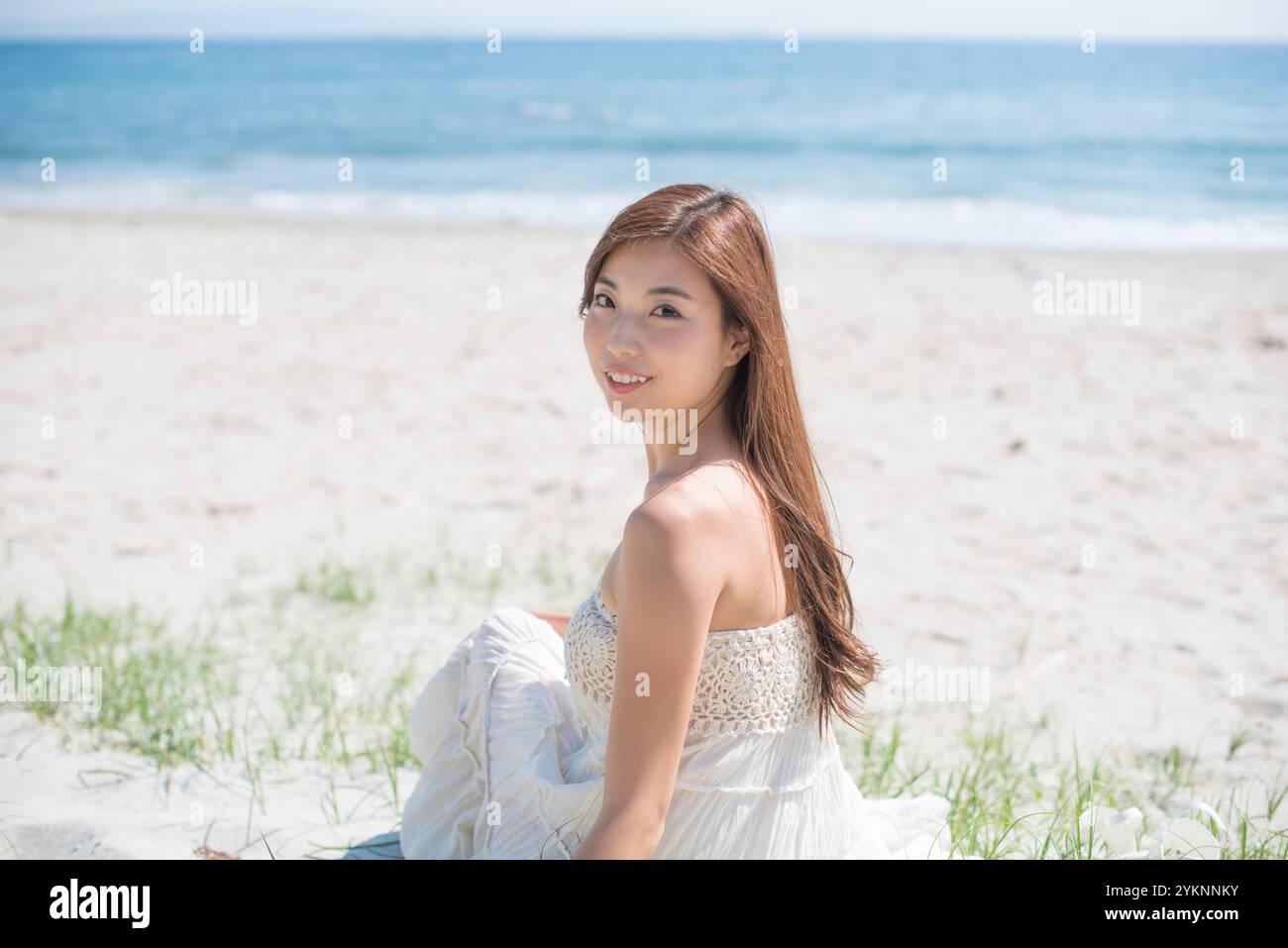 Frau, die am Sandstrand sitzt Stockfoto