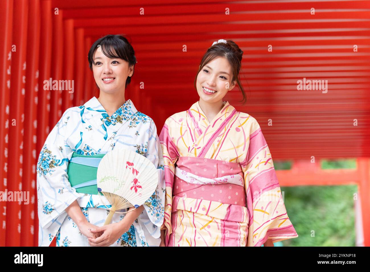 Zwei weibliche Schreine in Yukata, die durch das Torii-Tor des Schreins gehen Stockfoto