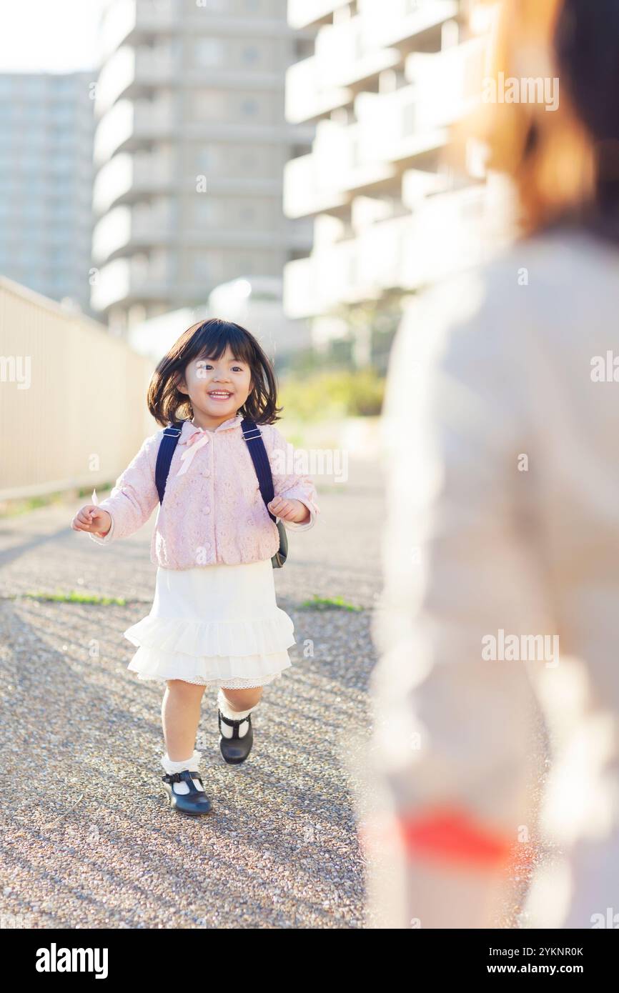 Kindergartenmädchen rennt auf die Mutter zu Stockfoto