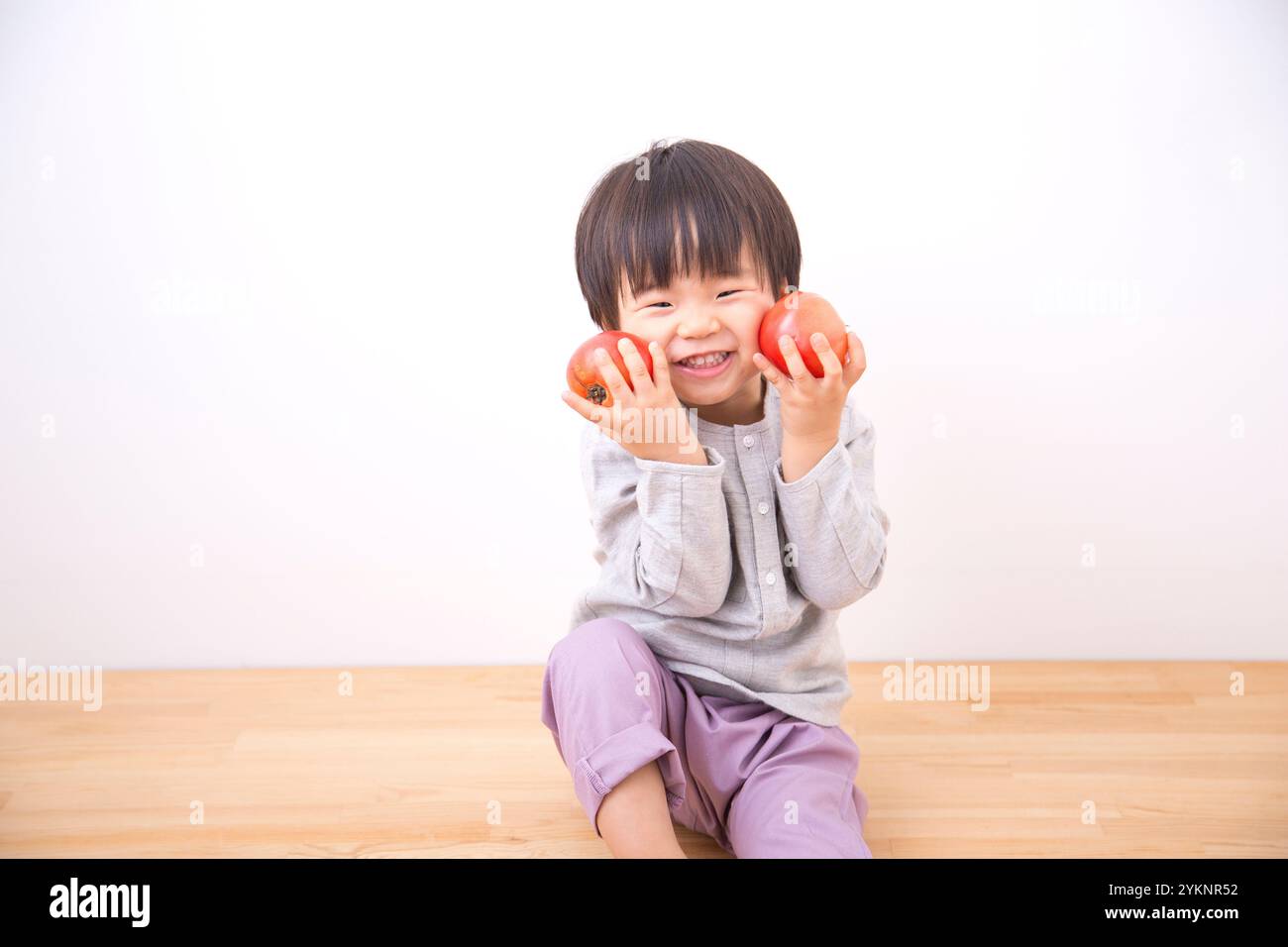 Junge, der Tomate in beiden Händen hält Stockfoto