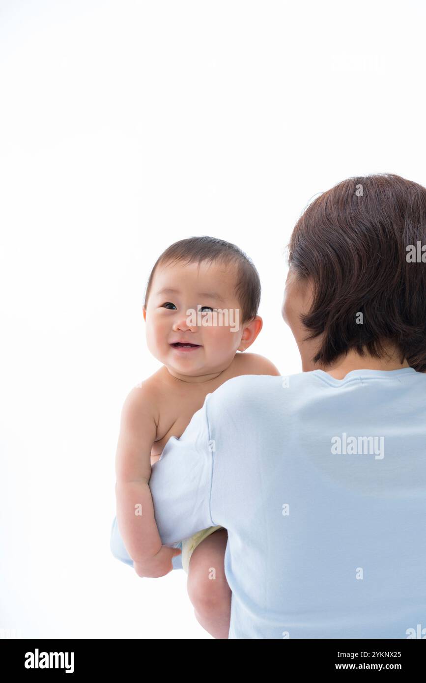 Das Baby lächelt über Mutters Schulter. Stockfoto