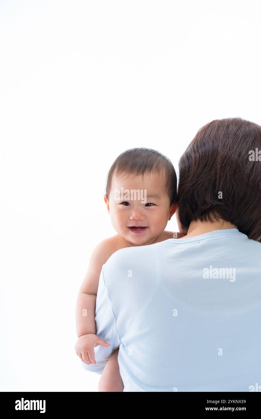 Das Baby lächelt über Mutters Schulter. Stockfoto