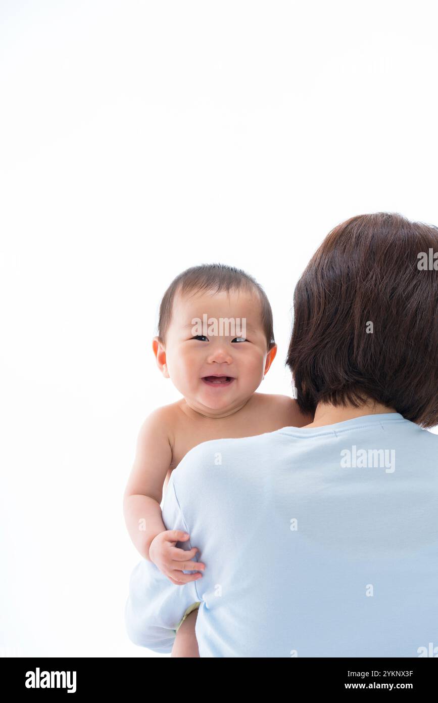 Das Baby lächelt über Mutters Schulter. Stockfoto