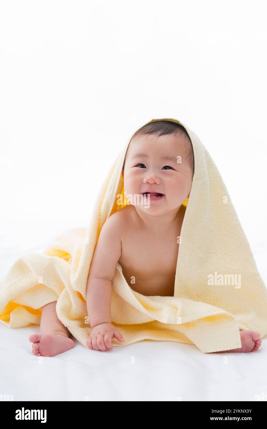 Baby in guter Laune auf einem gelben Handtuch. Stockfoto