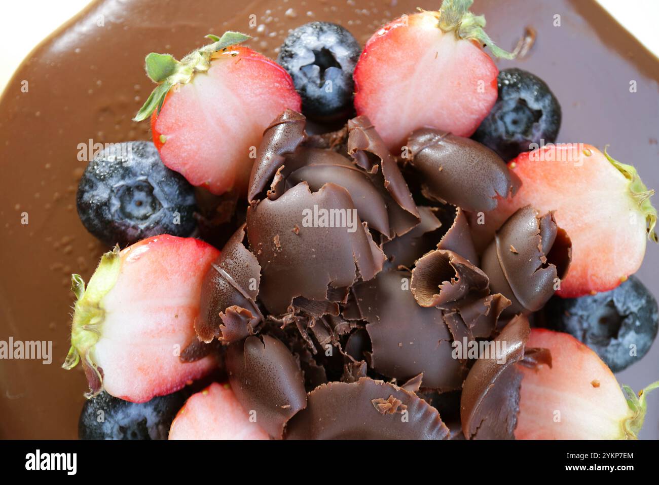 Blick von oben auf köstliche Schokoladenlocken mit frischen Beerenfrüchten auf Schokoladenkuchen Stockfoto