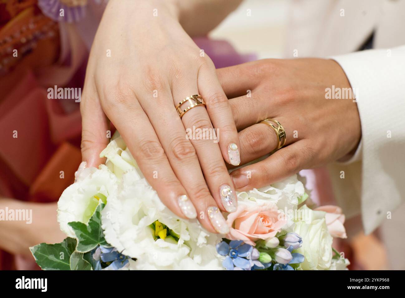 Braut und Bräutigam tragen Eheringe mit Handstrauß bei der Hochzeitszeremonie Stockfoto