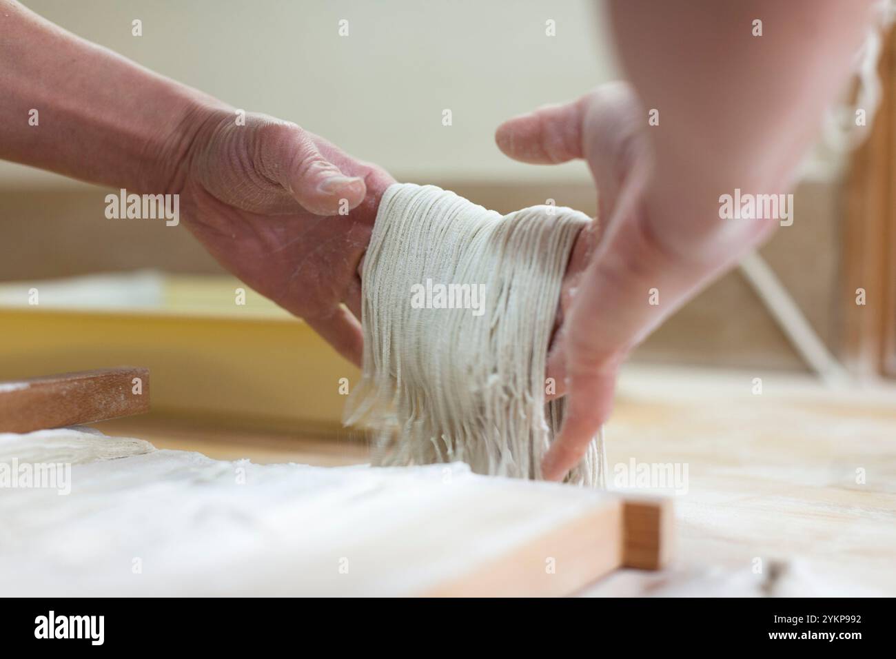 Hand eines Handwerkers, der Buchweizenteig schneidet und hebt Stockfoto