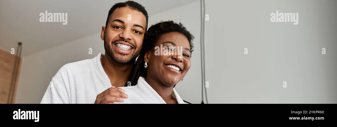 Ein fröhliches junges Paar lächelt in seinem Hotelzimmer und feiert die Liebe während des Urlaubs. Stockfoto