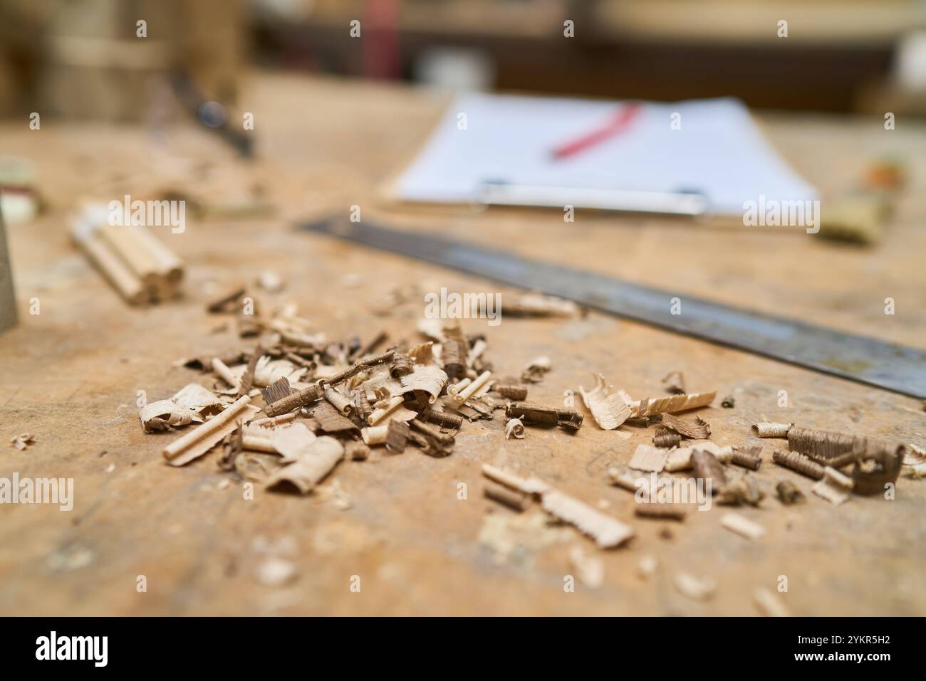 Detaillierte Ansicht der Holzspäne, die auf einer Werkbank in einer Tischlerei verstreut sind, und hebt die Handwerkskunst und die Holzbearbeitungswerkzeuge hervor. Perfekt für Illustrationen Stockfoto