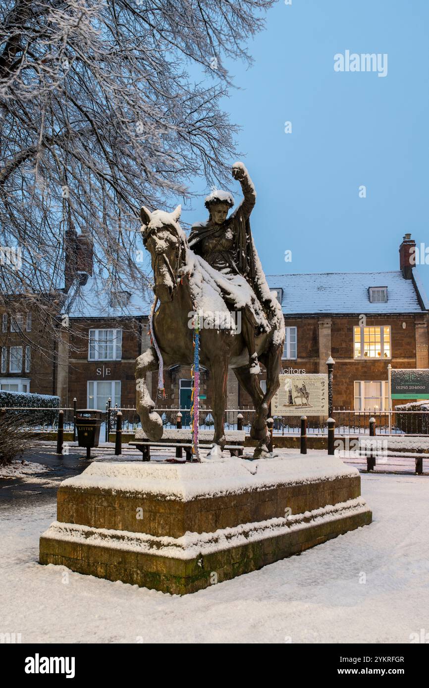 Schöne Dame Bronzestatue / Skulptur auf einem walisischen Spindelpferd neben Banbury Cross im Schnee bei Sonnenaufgang. Banbury, Oxfordshire, England Stockfoto