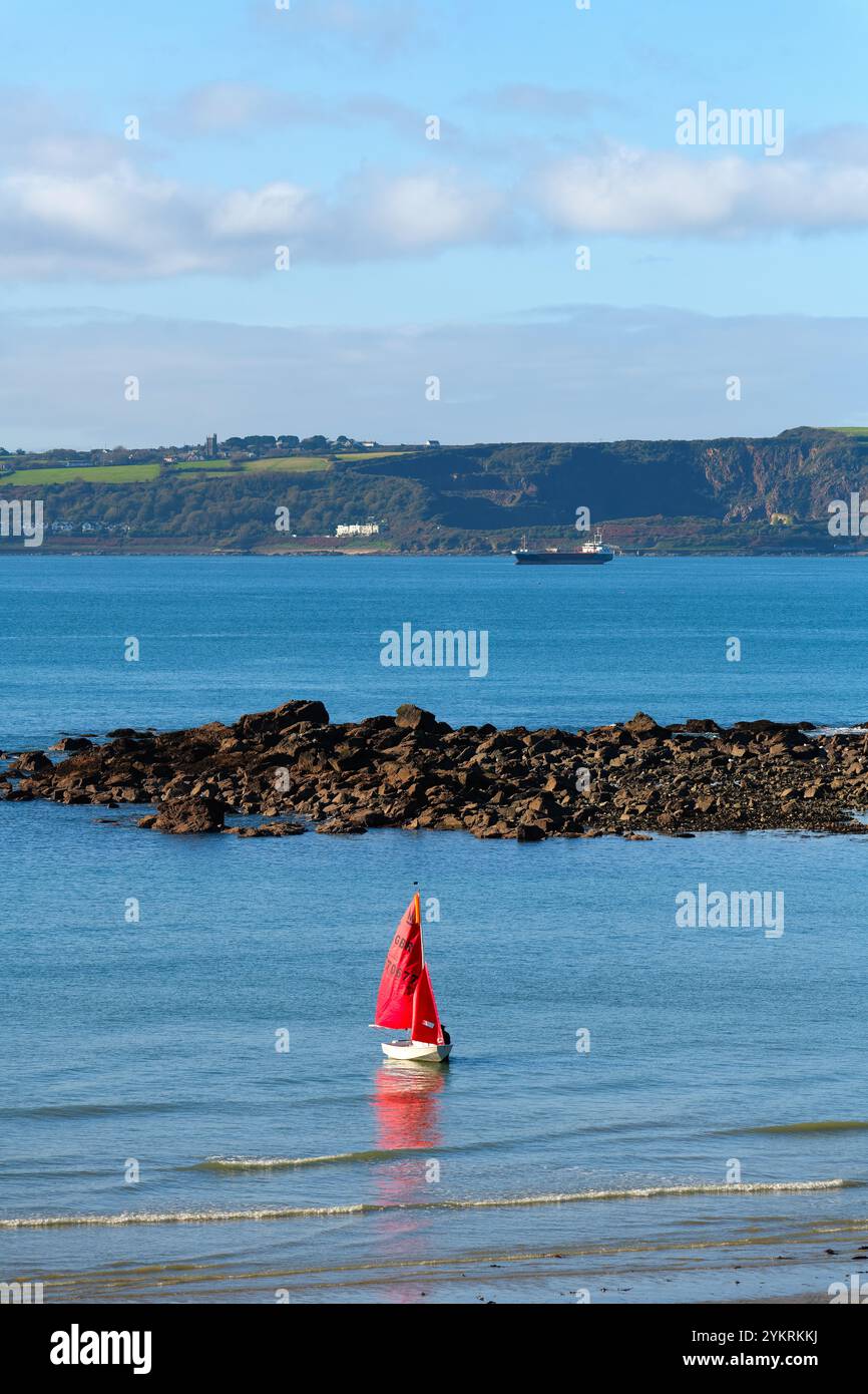 Eine einsame Jacht mit roten Segeln, die am Strand von Marazion Cornwall England, Großbritannien, starten Stockfoto