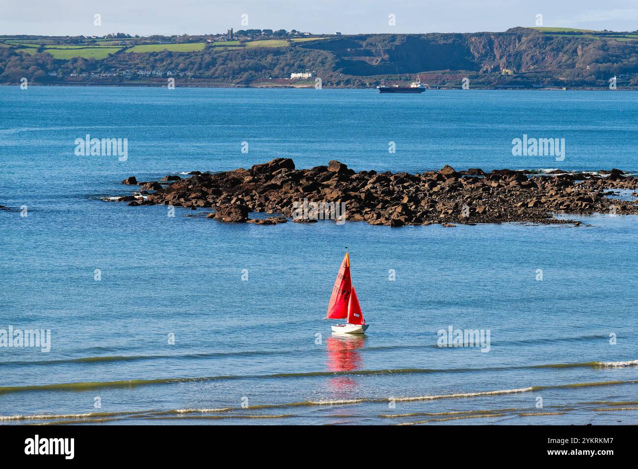 Eine einsame Jacht mit roten Segeln, die am Strand von Marazion Cornwall England, Großbritannien, starten Stockfoto