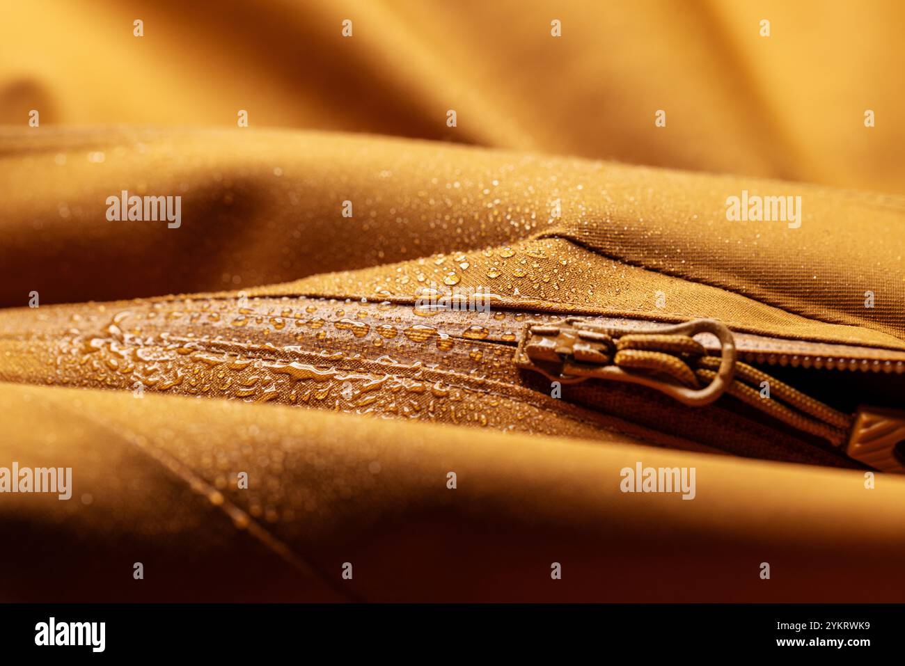 Wasserdichte Kleidung mit Wassertropfen – Nahaufnahme aus braunem, wasserabweisendem Material und Reißverschluss Stockfoto