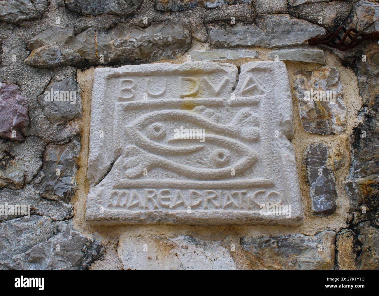 Steintafel mit zwei Fischen und einer Inschrift in der Altstadt von Budva. Historischer Ort in Montenegro Stockfoto