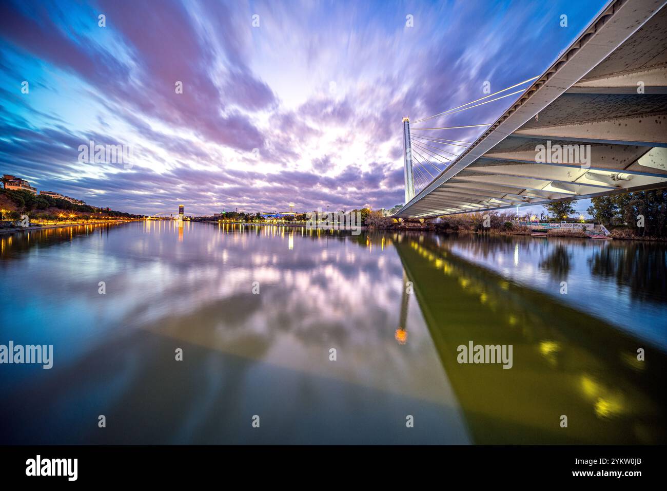 Wunderschöne Szene in der Abenddämmerung mit der beleuchteten Alamillo-Brücke über Rio Guadalquivir in Sevilla, Spanien. Die Reflexion auf dem Wasser verleiht Ruhe Stockfoto