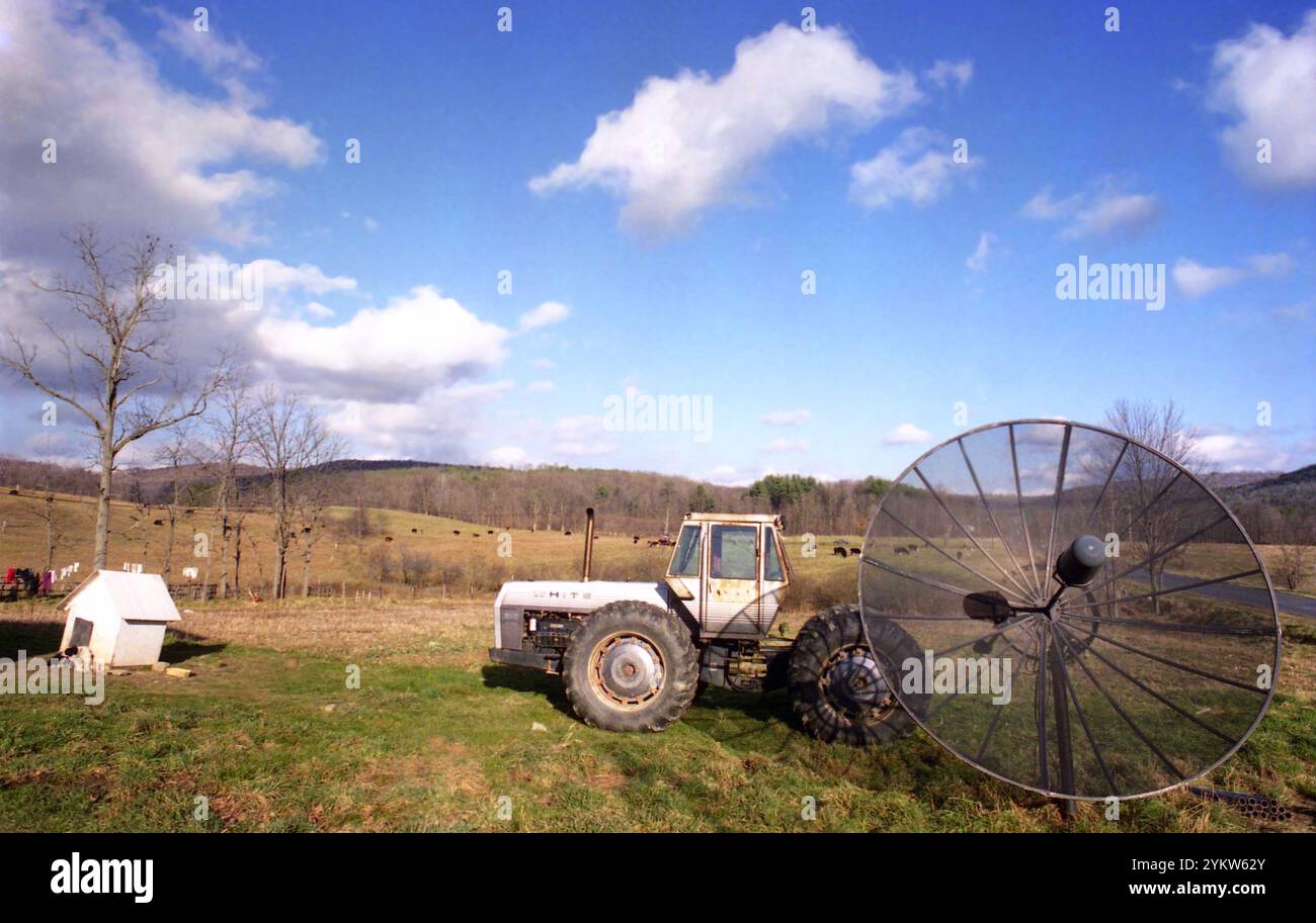 Bundesstaat New York, USA, ca. 1992. Ein weißer 4-210-Traktor, eine große Antenne und ein Hundehaus auf einem ländlichen Grundstück. Stockfoto