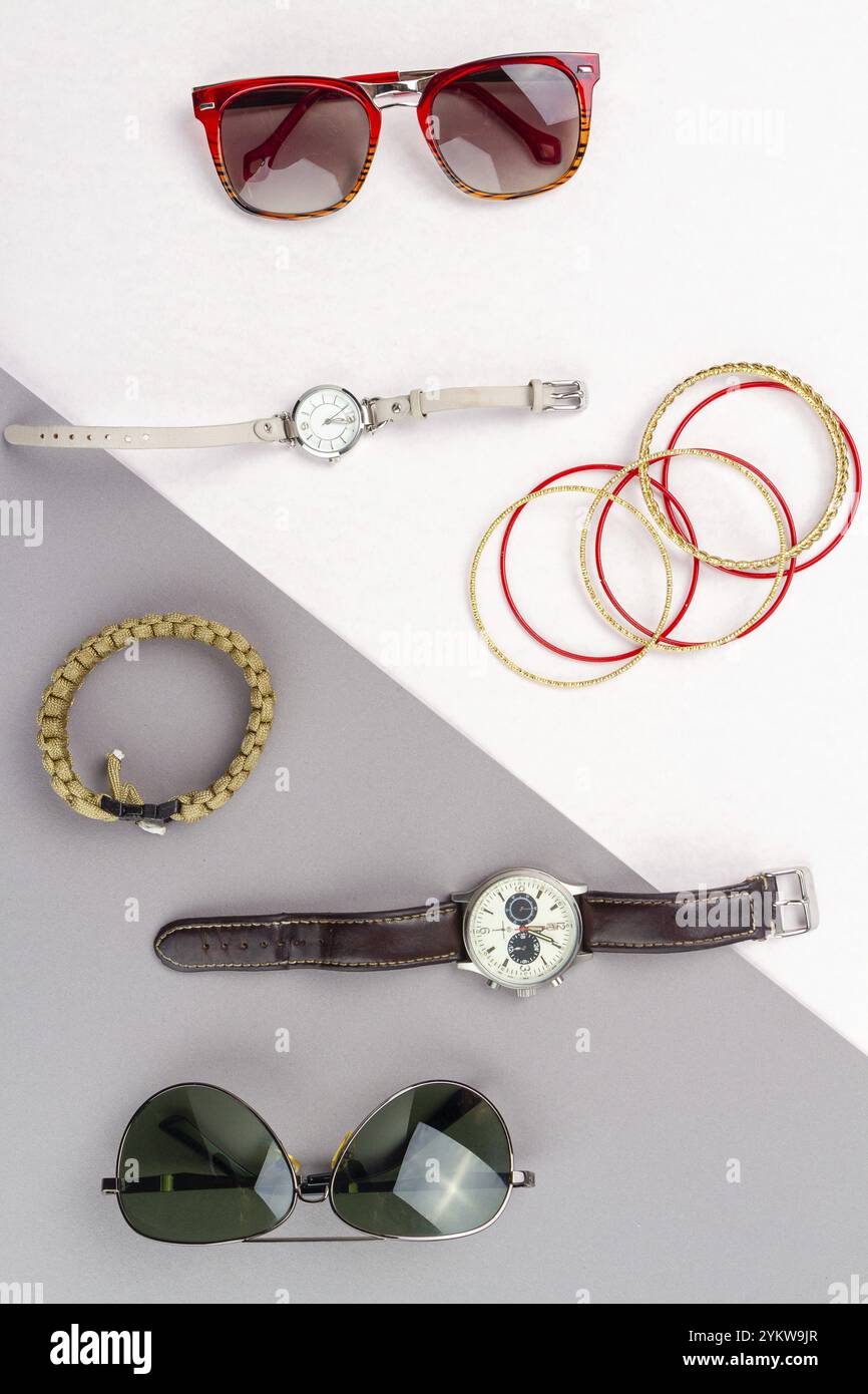 Flache Kontraste von Herren- und Damenaccessoires. Draufsicht-Brille mit Uhr und Armbändern Stockfoto