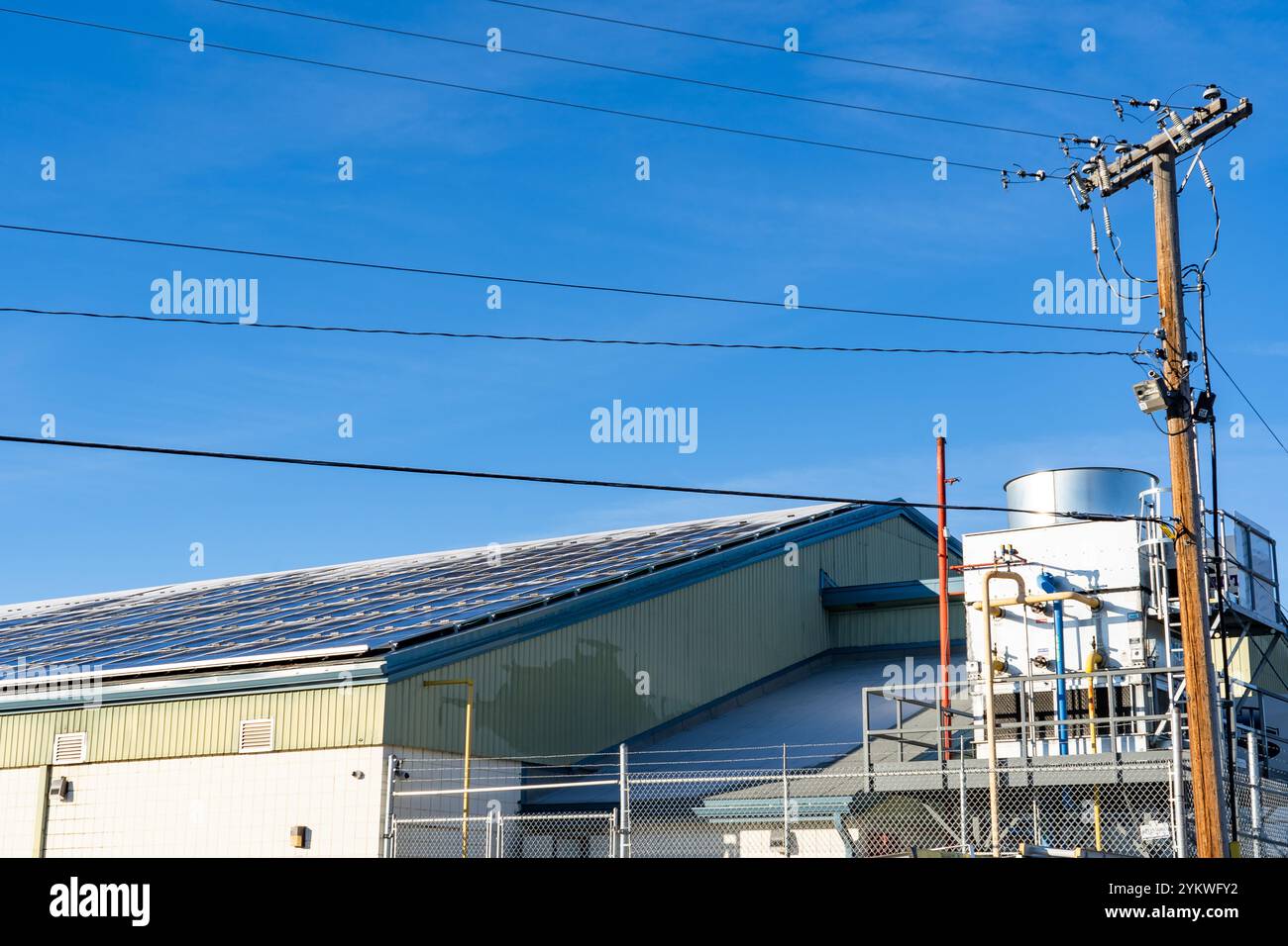 Solarpaneele mit Schneesichern erzeugen Strom mit Stromleitungen und Eisanlagen in einem örtlichen Gemeindezentrum und einer Eishockeybahn in Calgary Albert Stockfoto