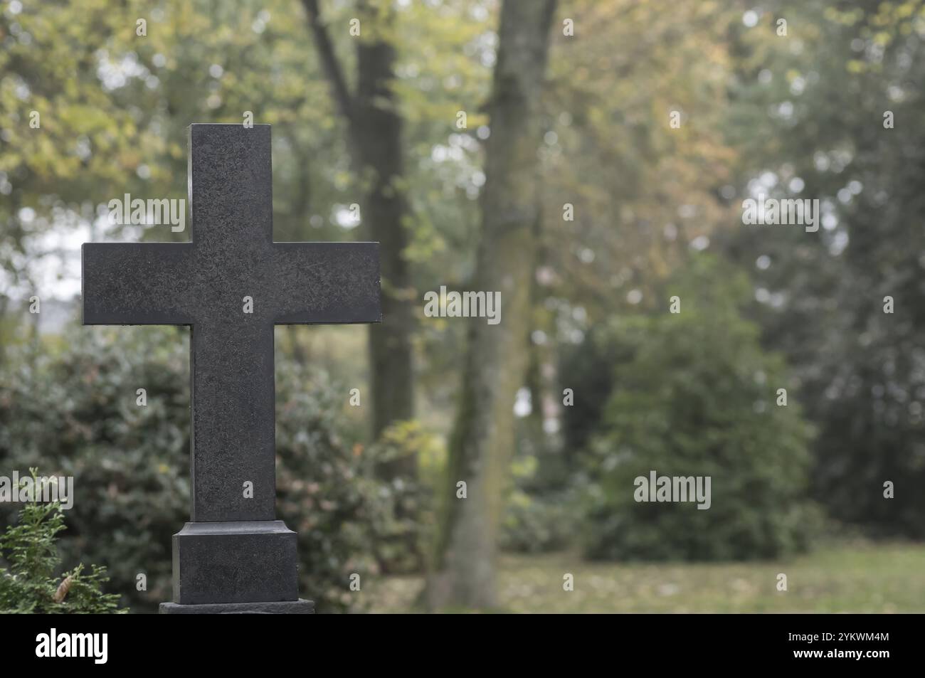 Steinkreuz auf einem Friedhof, symbolisiert Glauben, Erinnerung und den Zyklus von Leben und Tod Stockfoto
