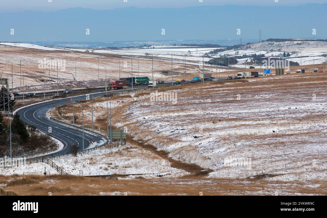 Ein schneebedecktes Ende des Tages auf der M62, als sie den höchsten Teil ihrer Länge in den Pennines zwischen Rochdale und Huddersfield überquert. Die M62 ist eine 107 Meilen (172 km) lange Trans-Pennine-Autobahn in Nordengland, die Liverpool und Hull über Manchester, Bradford, Leeds und Wakefield verbindet. Stockfoto