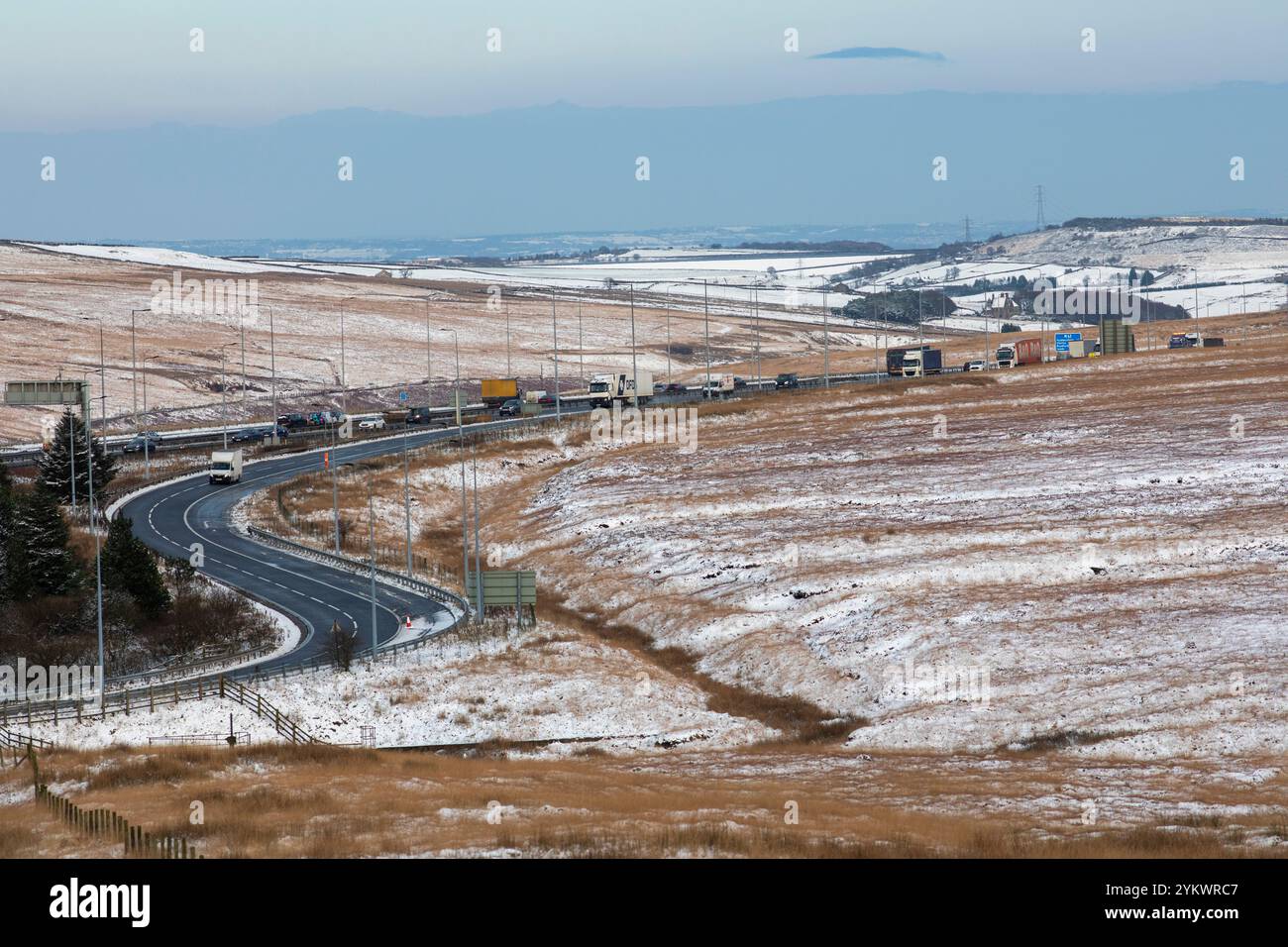 Ein schneebedecktes Ende des Tages auf der M62, als sie den höchsten Teil ihrer Länge in den Pennines zwischen Rochdale und Huddersfield überquert. Die M62 ist eine 107 Meilen (172 km) lange Trans-Pennine-Autobahn in Nordengland, die Liverpool und Hull über Manchester, Bradford, Leeds und Wakefield verbindet. Stockfoto