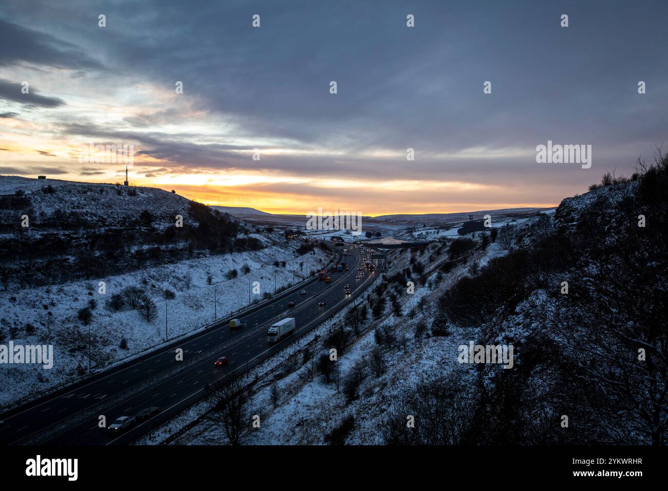 Ein schneebedecktes Ende des Tages auf der M62, als sie den höchsten Teil ihrer Länge in den Pennines zwischen Rochdale und Huddersfield überquert. Die M62 ist eine 107 Meilen (172 km) lange Trans-Pennine-Autobahn in Nordengland, die Liverpool und Hull über Manchester, Bradford, Leeds und Wakefield verbindet. Stockfoto