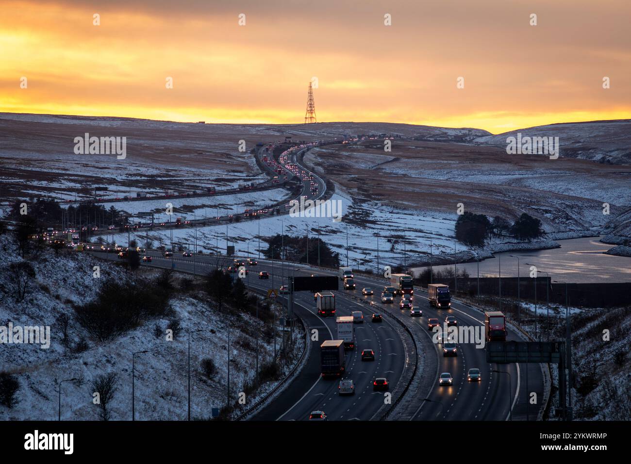 Ein schneebedecktes Ende des Tages auf der M62, als sie den höchsten Teil ihrer Länge in den Pennines zwischen Rochdale und Huddersfield überquert. Die M62 ist eine 107 Meilen (172 km) lange Trans-Pennine-Autobahn in Nordengland, die Liverpool und Hull über Manchester, Bradford, Leeds und Wakefield verbindet. Stockfoto