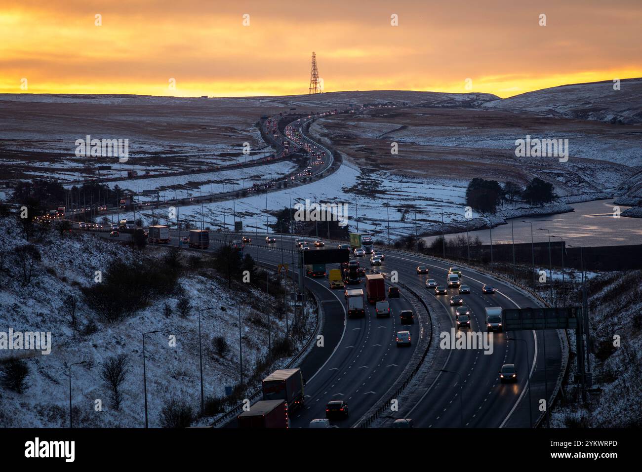 Ein schneebedecktes Ende des Tages auf der M62, als sie den höchsten Teil ihrer Länge in den Pennines zwischen Rochdale und Huddersfield überquert. Die M62 ist eine 107 Meilen (172 km) lange Trans-Pennine-Autobahn in Nordengland, die Liverpool und Hull über Manchester, Bradford, Leeds und Wakefield verbindet. Stockfoto
