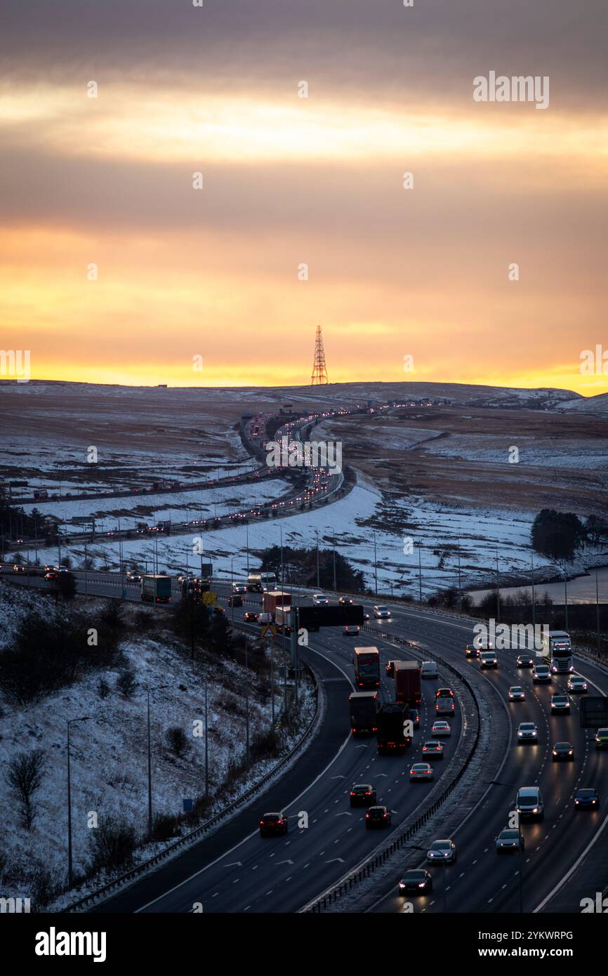 Ein schneebedecktes Ende des Tages auf der M62, als sie den höchsten Teil ihrer Länge in den Pennines zwischen Rochdale und Huddersfield überquert. Die M62 ist eine 107 Meilen (172 km) lange Trans-Pennine-Autobahn in Nordengland, die Liverpool und Hull über Manchester, Bradford, Leeds und Wakefield verbindet. Stockfoto