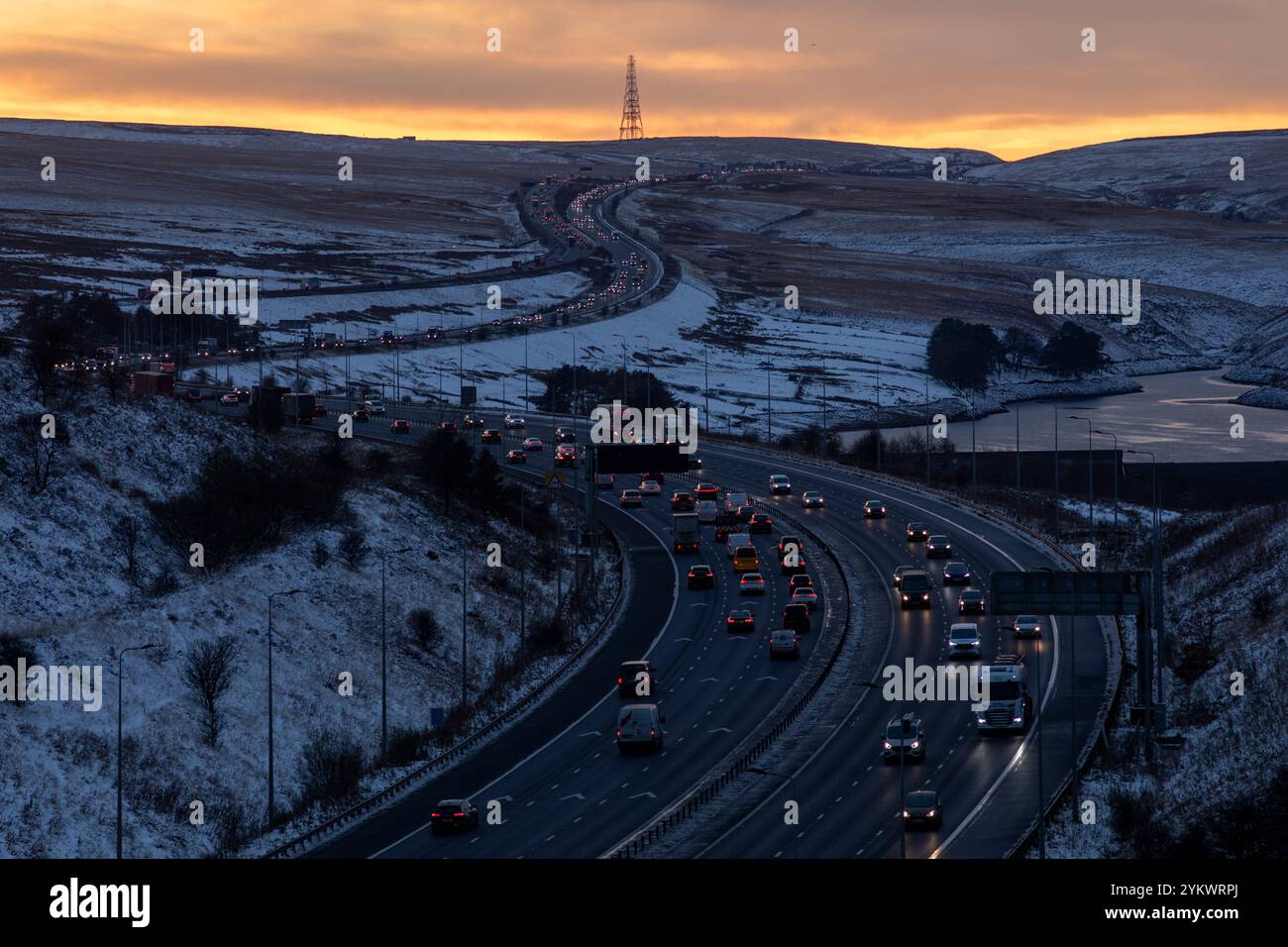 Ein schneebedecktes Ende des Tages auf der M62, als sie den höchsten Teil ihrer Länge in den Pennines zwischen Rochdale und Huddersfield überquert. Die M62 ist eine 107 Meilen (172 km) lange Trans-Pennine-Autobahn in Nordengland, die Liverpool und Hull über Manchester, Bradford, Leeds und Wakefield verbindet. Stockfoto