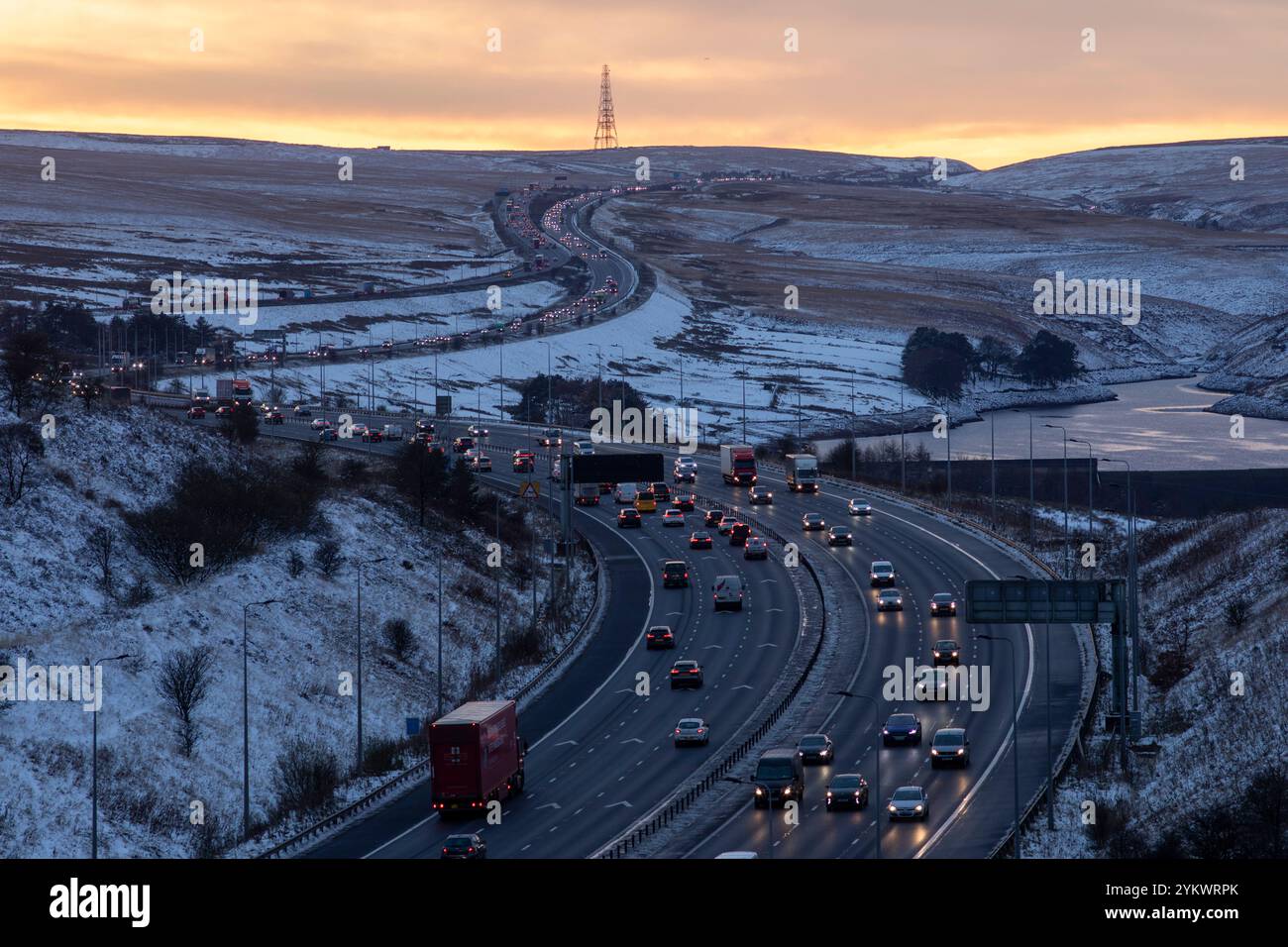 Ein schneebedecktes Ende des Tages auf der M62, als sie den höchsten Teil ihrer Länge in den Pennines zwischen Rochdale und Huddersfield überquert. Die M62 ist eine 107 Meilen (172 km) lange Trans-Pennine-Autobahn in Nordengland, die Liverpool und Hull über Manchester, Bradford, Leeds und Wakefield verbindet. Stockfoto
