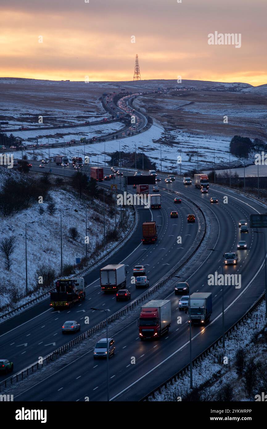 Ein schneebedecktes Ende des Tages auf der M62, als sie den höchsten Teil ihrer Länge in den Pennines zwischen Rochdale und Huddersfield überquert. Die M62 ist eine 107 Meilen (172 km) lange Trans-Pennine-Autobahn in Nordengland, die Liverpool und Hull über Manchester, Bradford, Leeds und Wakefield verbindet. Stockfoto