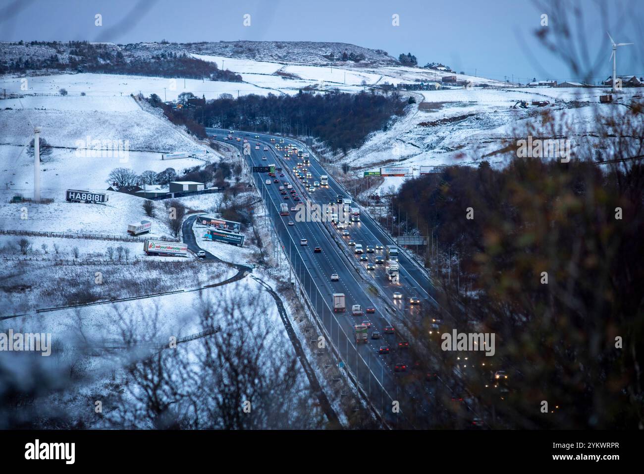 Ein schneebedecktes Ende des Tages auf der M62, als sie den höchsten Teil ihrer Länge in den Pennines zwischen Rochdale und Huddersfield überquert. Die M62 ist eine 107 Meilen (172 km) lange Trans-Pennine-Autobahn in Nordengland, die Liverpool und Hull über Manchester, Bradford, Leeds und Wakefield verbindet. Stockfoto