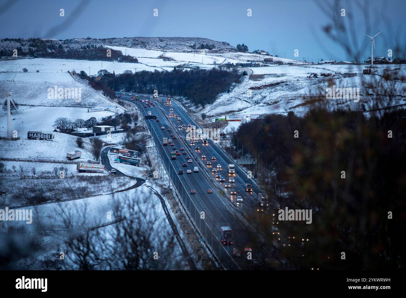 Ein schneebedecktes Ende des Tages auf der M62, als sie den höchsten Teil ihrer Länge in den Pennines zwischen Rochdale und Huddersfield überquert. Die M62 ist eine 107 Meilen (172 km) lange Trans-Pennine-Autobahn in Nordengland, die Liverpool und Hull über Manchester, Bradford, Leeds und Wakefield verbindet. Stockfoto