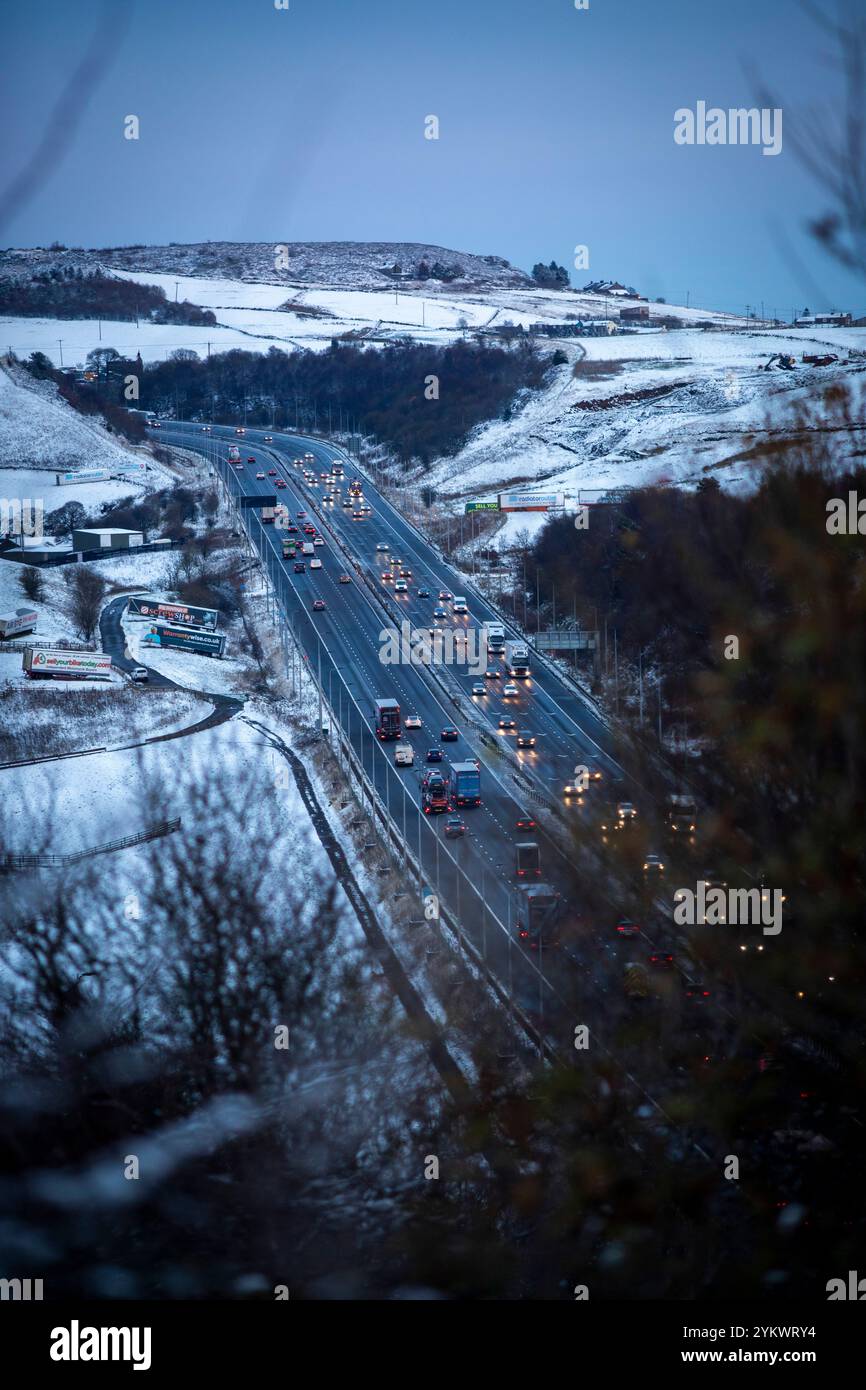 Ein schneebedecktes Ende des Tages auf der M62, als sie den höchsten Teil ihrer Länge in den Pennines zwischen Rochdale und Huddersfield überquert. Die M62 ist eine 107 Meilen (172 km) lange Trans-Pennine-Autobahn in Nordengland, die Liverpool und Hull über Manchester, Bradford, Leeds und Wakefield verbindet. Stockfoto