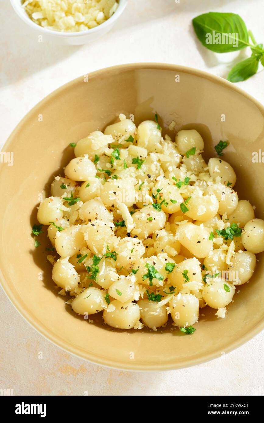 Kartoffelgnocchi mit Parmesankäse und Gemüse in der Schüssel auf hellem Hintergrund. Nahansicht Stockfoto