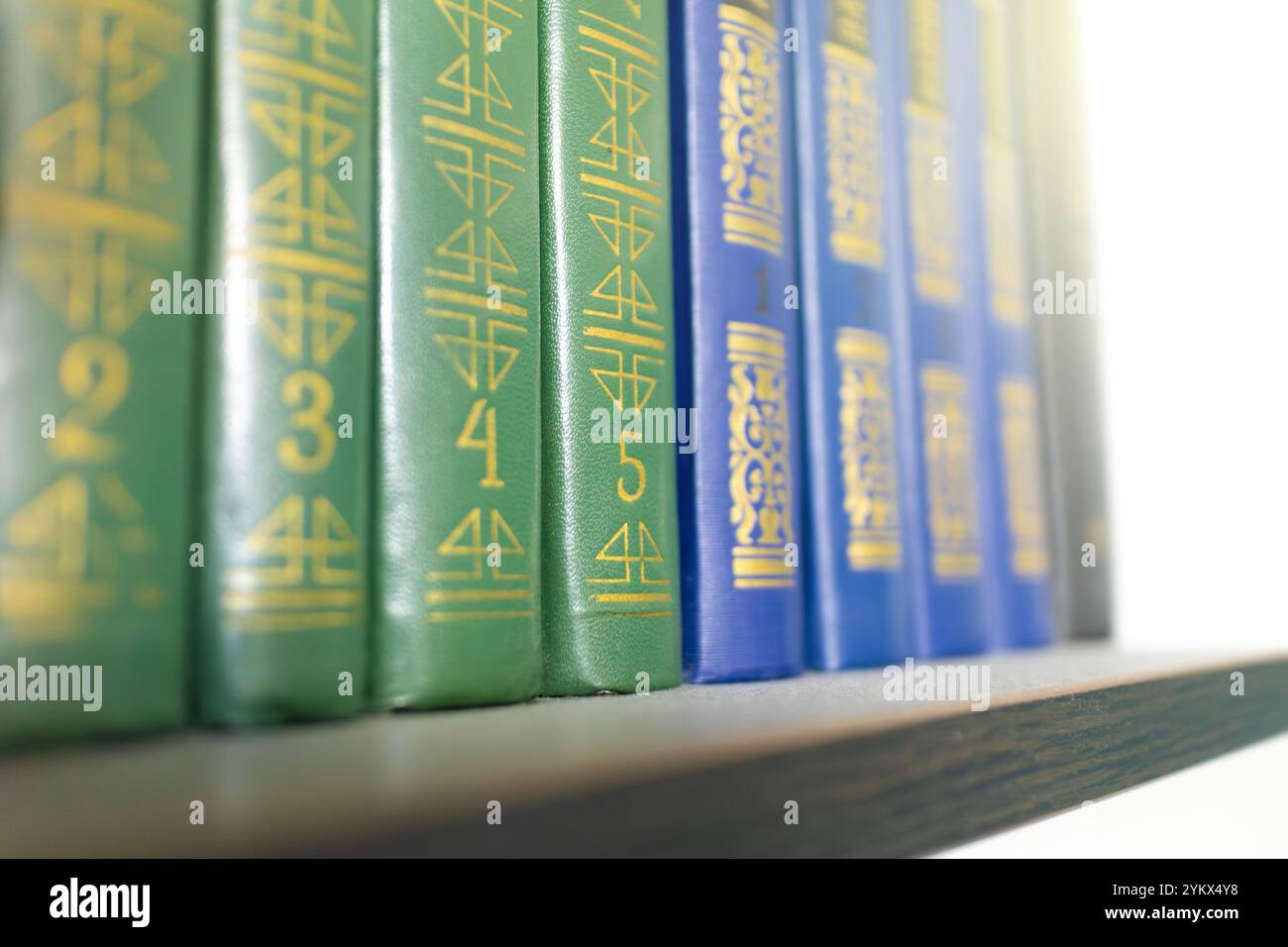 Eine Nahaufnahme der farbenfrohen Enzyklopädie-Bände, die auf einem Bücherregal angeordnet sind. Das Bild hebt die Stacheln mit goldenem Text hervor und zeigt eine ordentliche Organisation Stockfoto