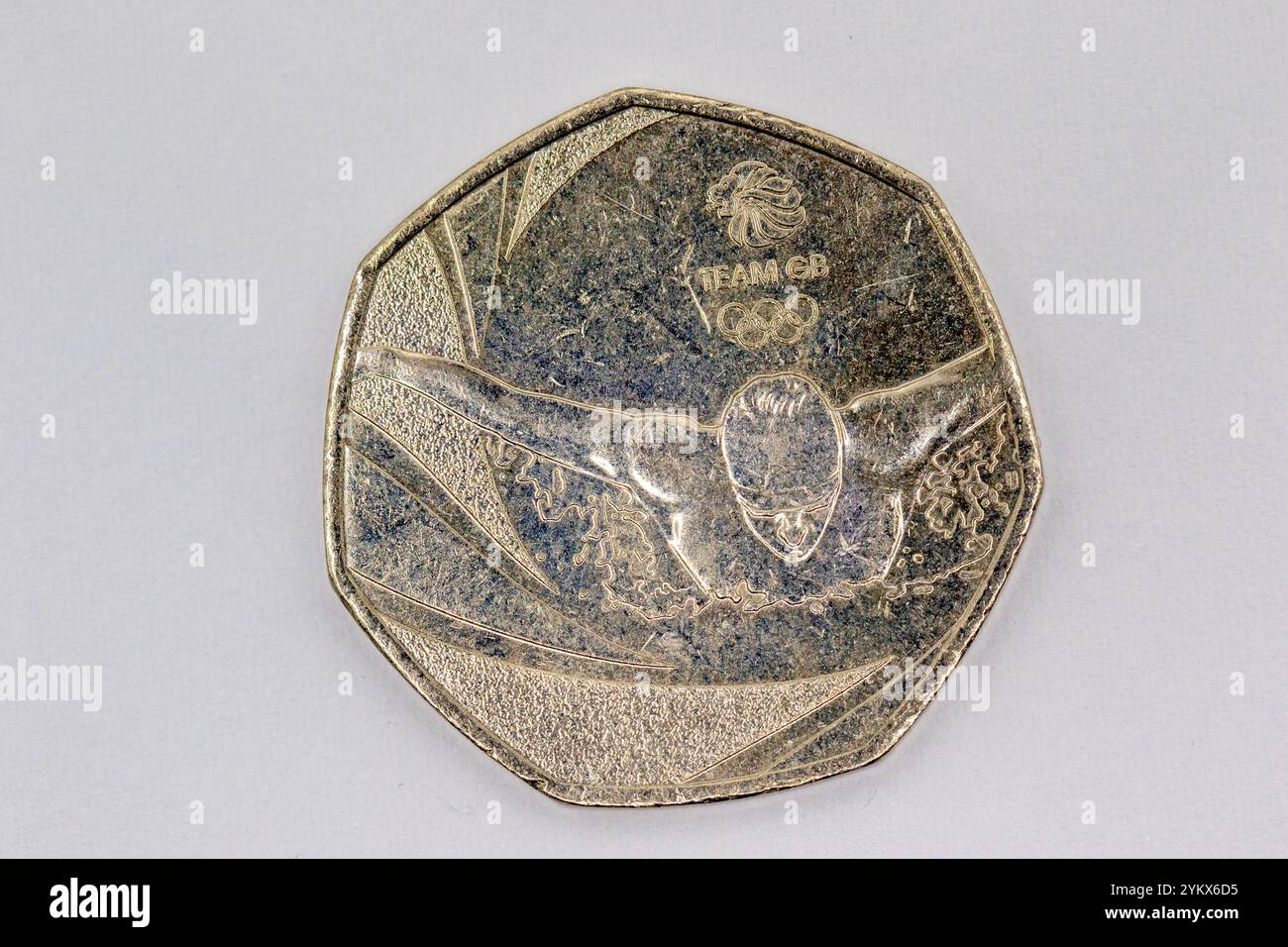 Nahaufnahme einer silberfarbenen, zwölfseitigen Münze, die einen Schwimmer darstellt. Die Münze ist mit dem Team GB-Logo und Olympischen Ringen versehen. Der Hintergrund ist Stockfoto