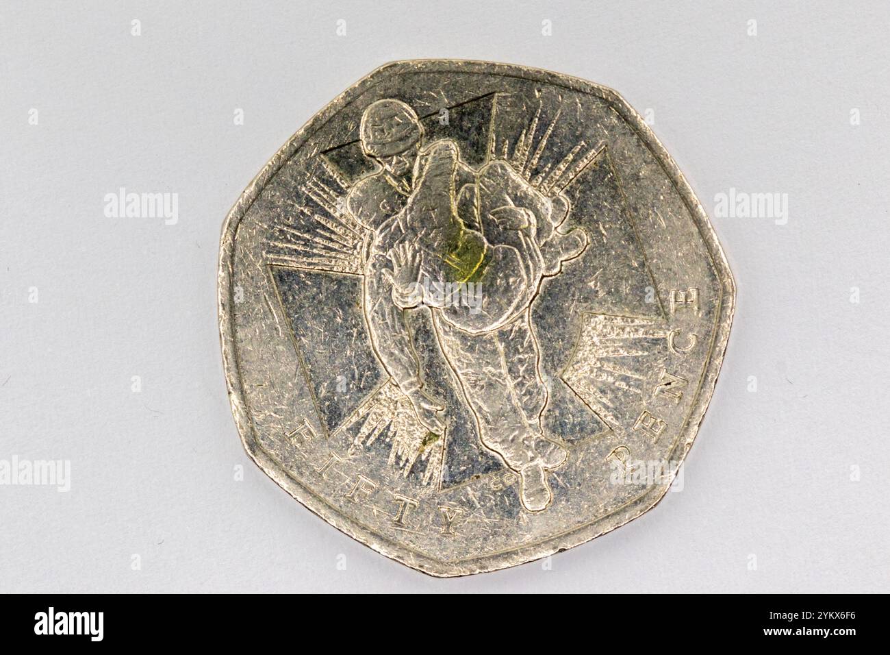 Nahaufnahme einer silberfarbenen 50-Pence-Münze, die einen Soldaten in dynamischer Pose darstellt, umgeben von stilisierten Strahlen, die von einem zentralen Kreuz ausgehen. Die Stockfoto
