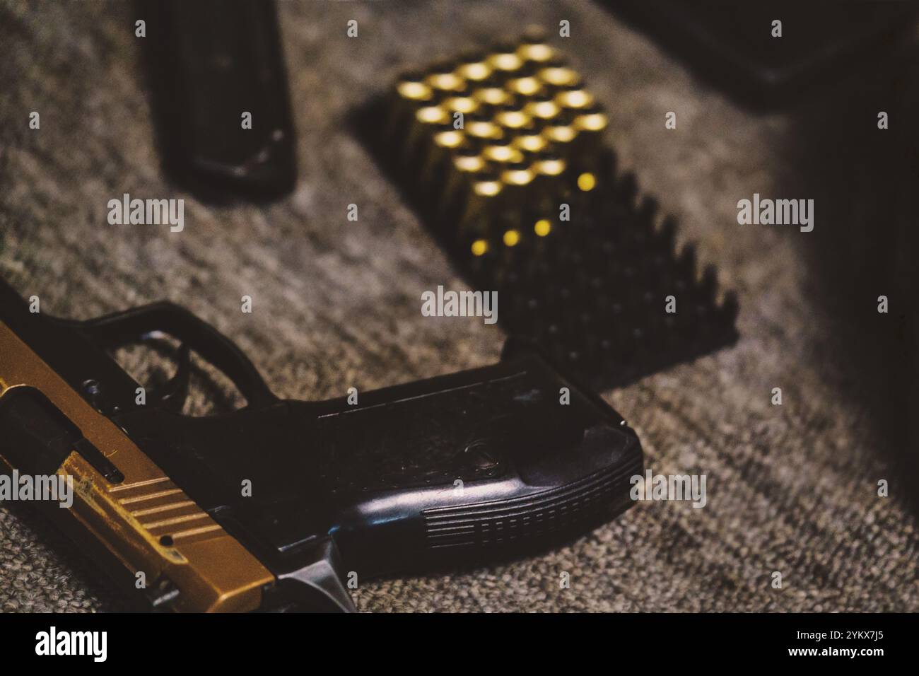 Handpistole mit Munitionsrunden, die ordentlich auf dem Tablett angeordnet sind, dunkle Hintergrundelemente verbessern die Atmosphäre Stockfoto