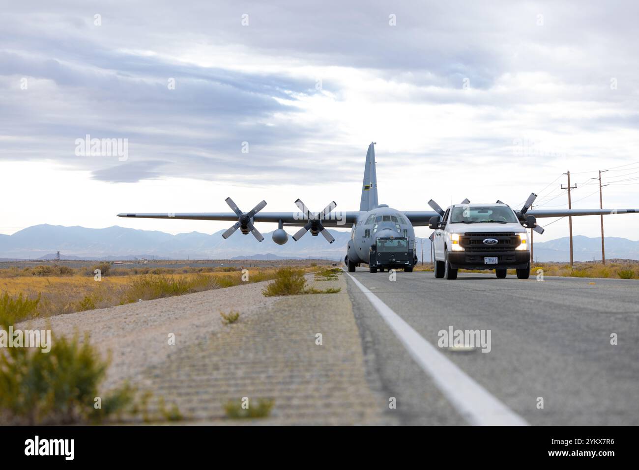 Flugfeldoperationen und Sicherheitskräfte eskortieren Freiwillige im Museum, während sie eine C-130E auf der Edwards Air Force Base die Straße hinunterschleppen. Das historische Flugzeug mit Stockfoto