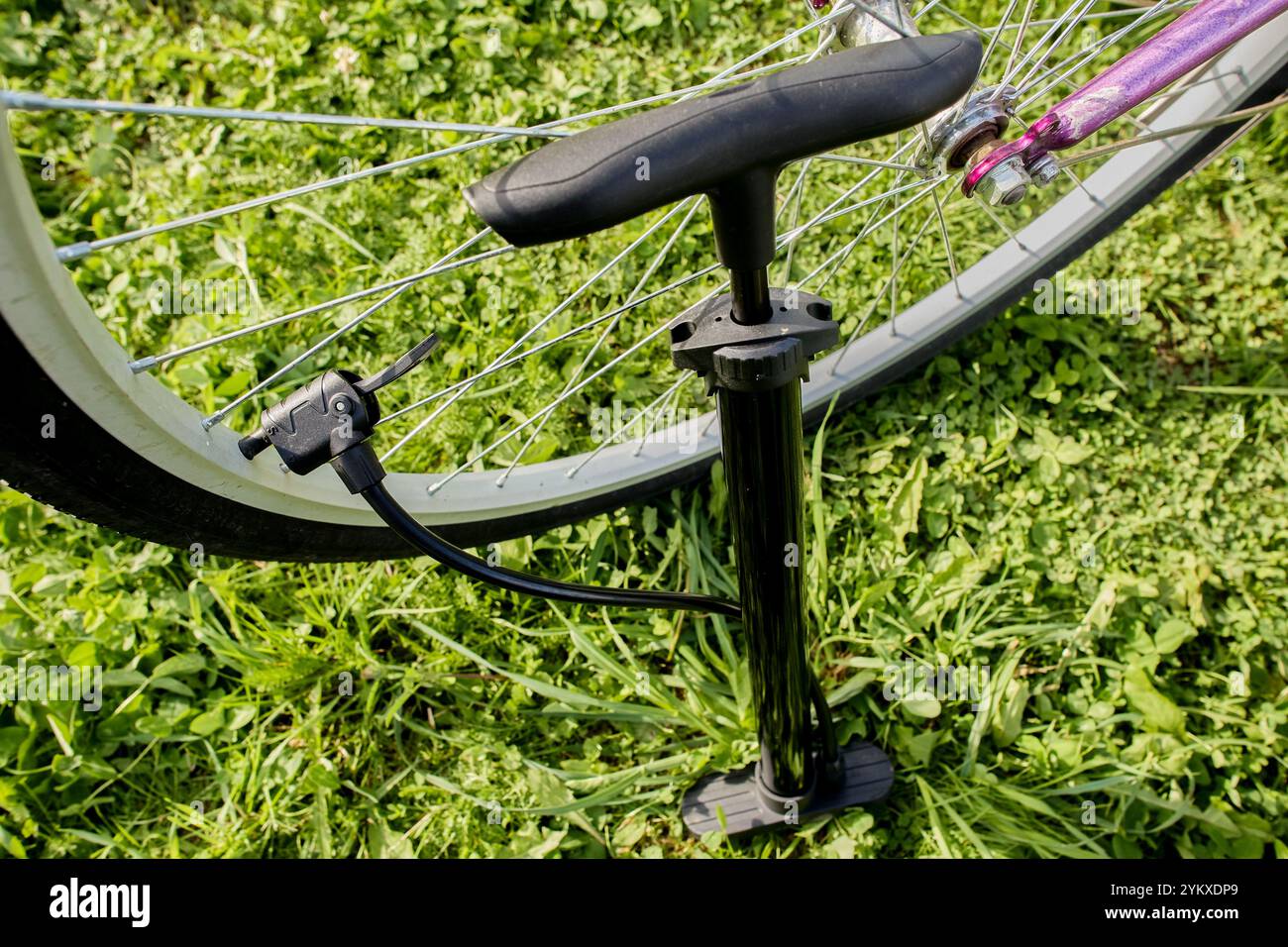 Aufpumpen von Fahrradreifen mit Luft mithilfe einer Bodenpumpe mit Universalkopf und Hebelklemme. Stockfoto